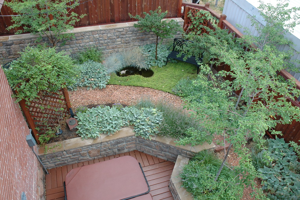 This is an example of a small bohemian back xeriscape full sun garden for summer in Salt Lake City with a retaining wall and natural stone paving.
