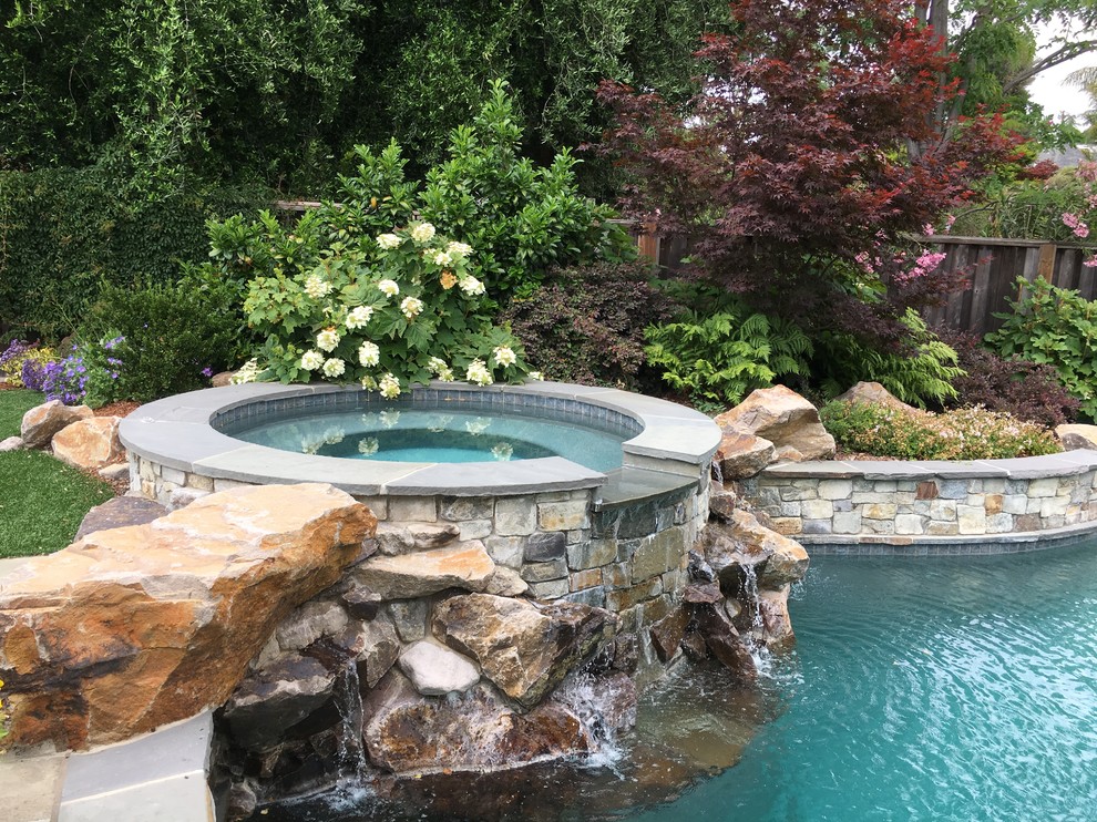 Ejemplo de piscina actual grande en patio trasero con adoquines de piedra natural