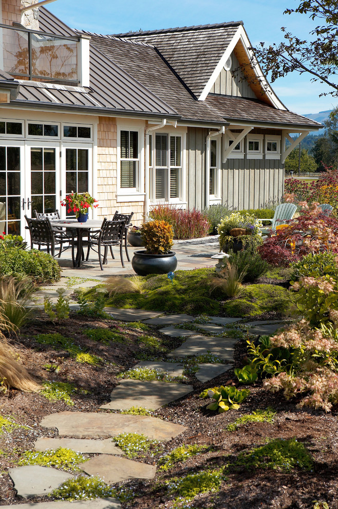 Aménagement d'un jardin arrière campagne avec des pavés en pierre naturelle.