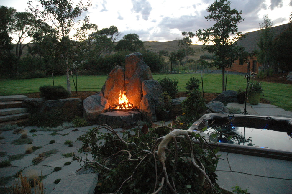 Photo of a large rustic full sun backyard stone formal garden in Denver with a fire pit.
