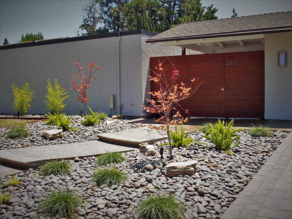 Photo of a midcentury front xeriscape garden in Orange County with a garden path and concrete paving.