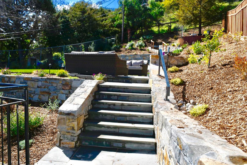 Diseño de jardín de secano clásico renovado grande en patio trasero con adoquines de piedra natural, muro de contención y exposición parcial al sol