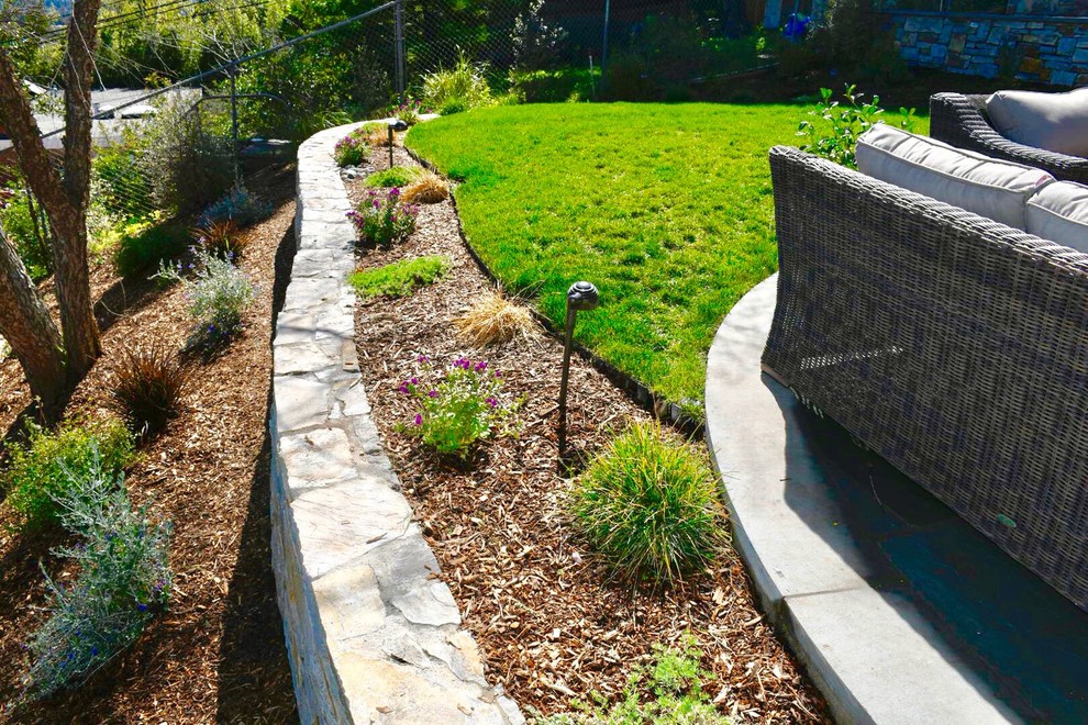 Ispirazione per un grande giardino xeriscape tradizionale esposto a mezz'ombra dietro casa con un muro di contenimento e pavimentazioni in pietra naturale