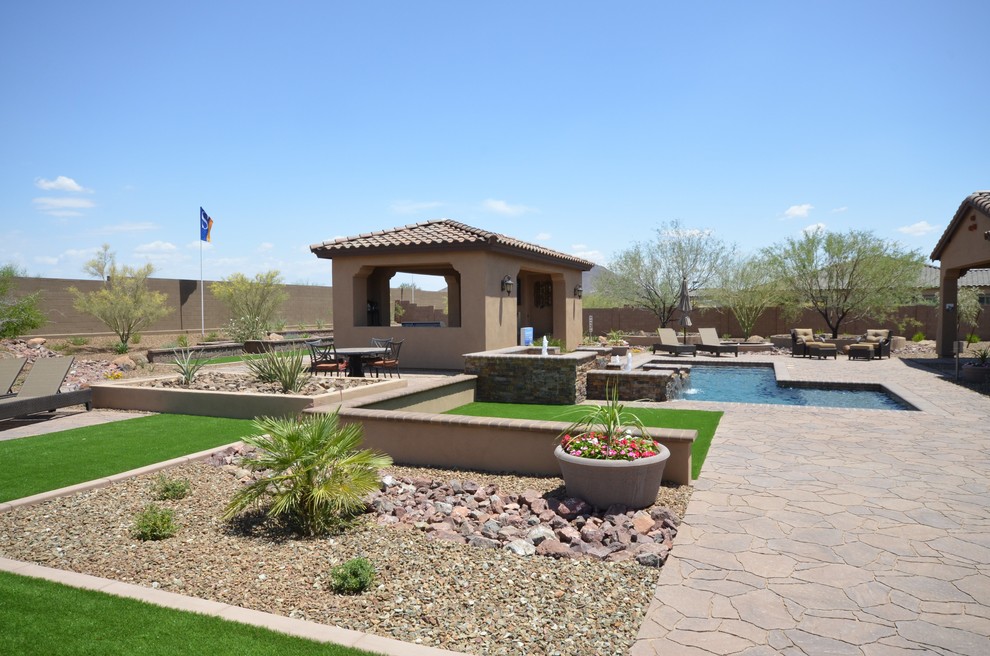 This is an example of an expansive mediterranean back full sun garden in Phoenix with an outdoor sport court and natural stone paving.