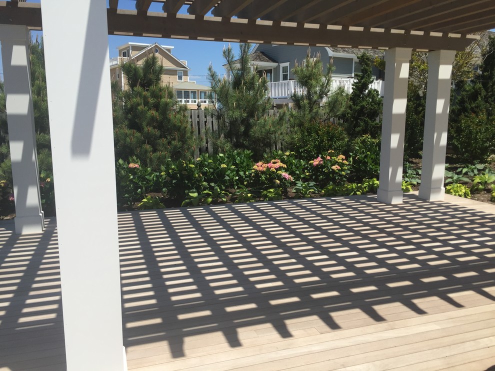Design ideas for a coastal full sun backyard landscaping in New York with decking for summer.