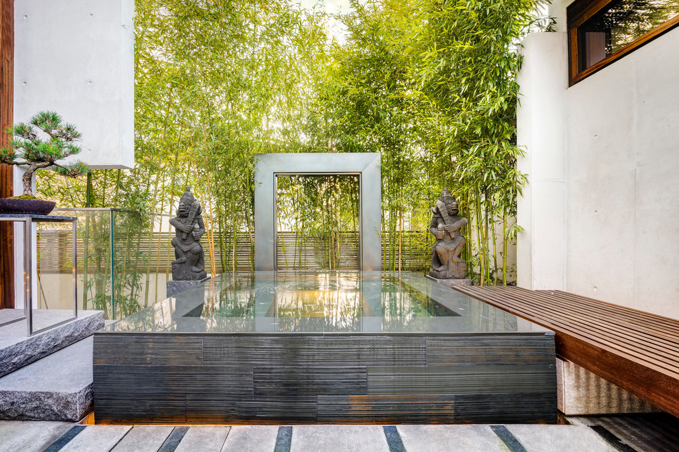 Diseño de jardín asiático de tamaño medio en verano en patio trasero con fuente, exposición parcial al sol y adoquines de piedra natural