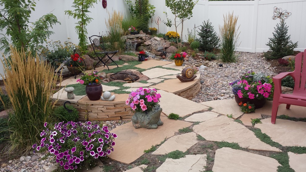 This is an example of a small mediterranean full sun backyard stone water fountain landscape in Denver for summer.