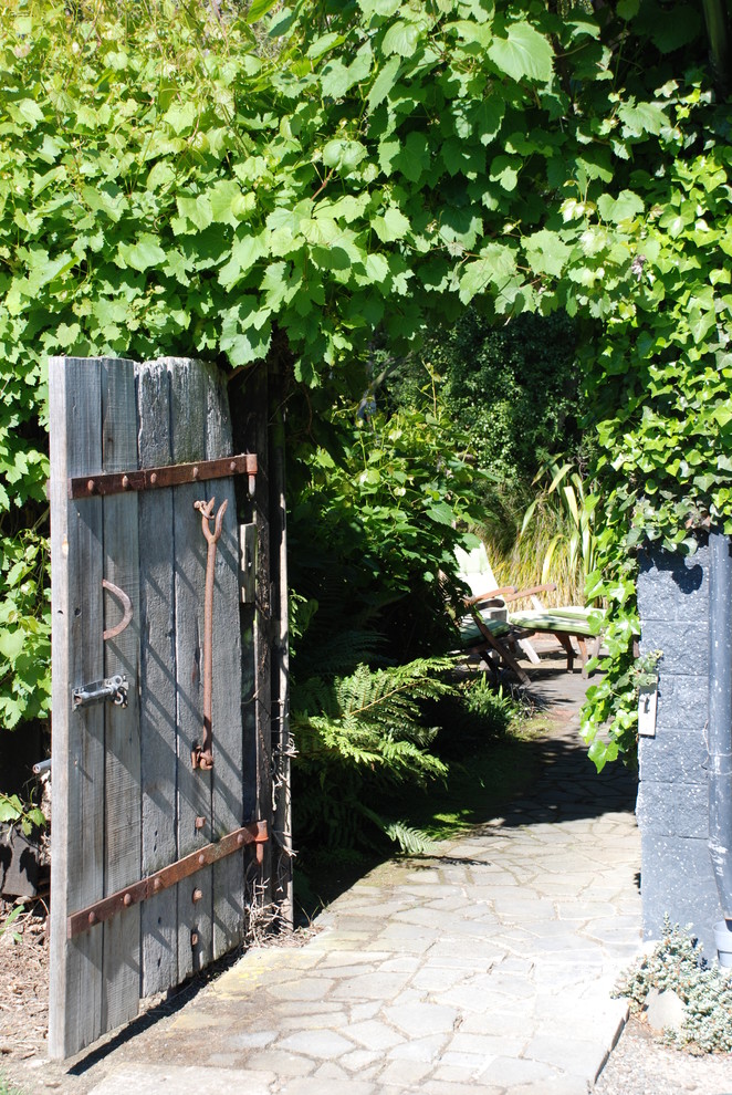 Foto på en rustik bakgård, med naturstensplattor och en trädgårdsgång