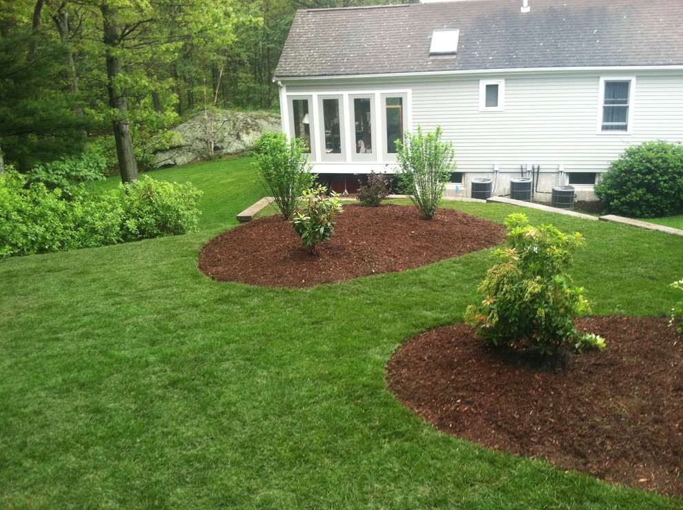 Photo of a medium sized traditional back full sun garden for spring in Boston with a retaining wall and mulch.