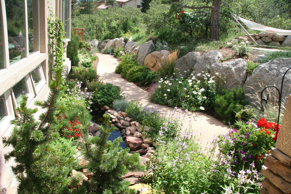 Immagine di un grande giardino formale boho chic esposto in pieno sole dietro casa in primavera con un ingresso o sentiero e pavimentazioni in cemento