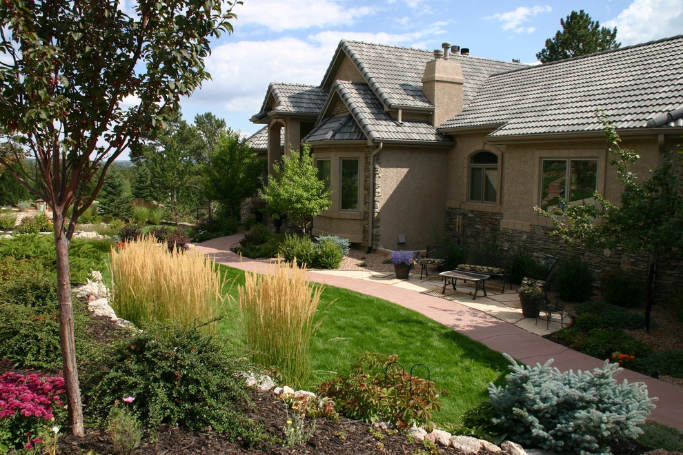 This is an example of a large eclectic front xeriscape fully shaded garden for autumn in Denver with a garden path and natural stone paving.