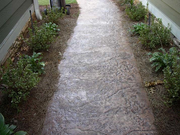 Inredning av en trädgård längs med huset, med marksten i betong