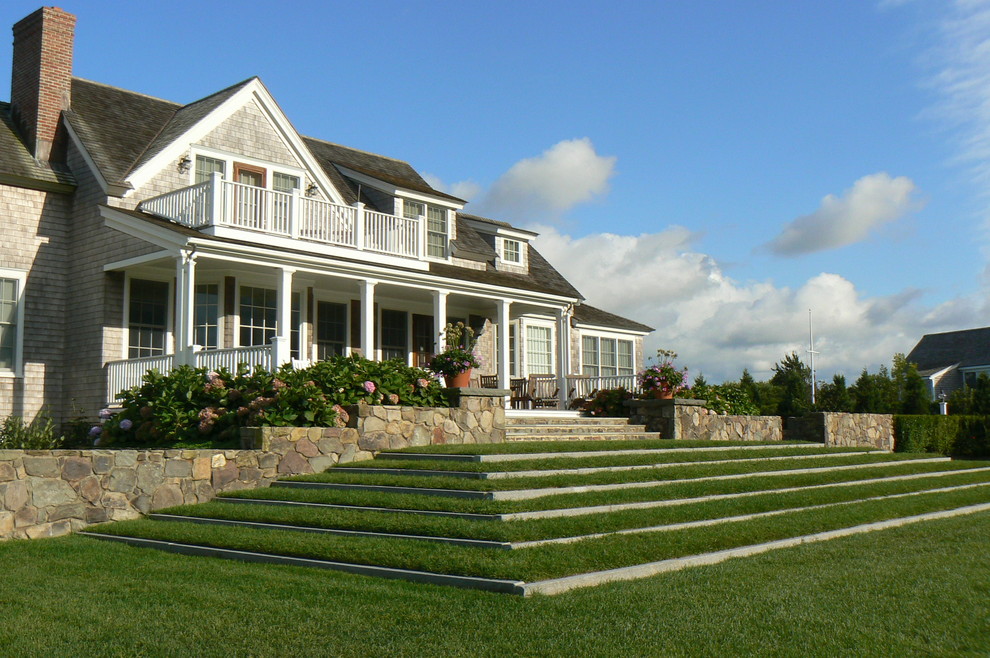 Стильный дизайн: большой солнечный регулярный сад на заднем дворе в морском стиле с подпорной стенкой, хорошей освещенностью и покрытием из каменной брусчатки - последний тренд