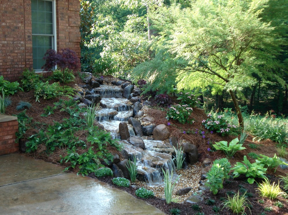 Immagine di un giardino formale chic esposto a mezz'ombra di medie dimensioni e davanti casa in estate con pavimentazioni in pietra naturale e una cascata