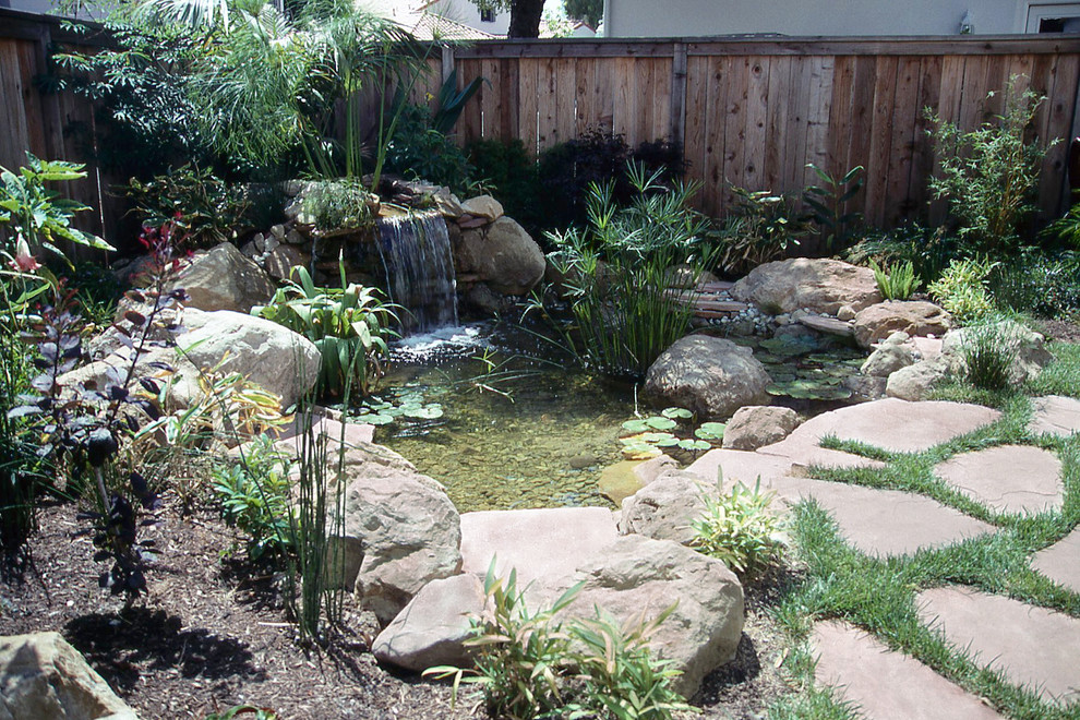 Diseño de jardín de estilo americano pequeño en verano en patio con fuente, adoquines de piedra natural, jardín francés y exposición parcial al sol