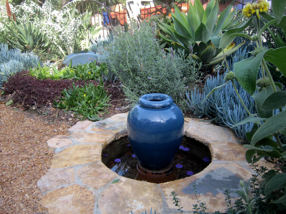 Photo of a medium sized side formal full sun garden for summer in Santa Barbara with a water feature and natural stone paving.