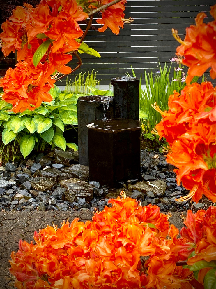 Foto de jardín rústico en patio trasero con fuente, exposición parcial al sol, adoquines de hormigón y con madera