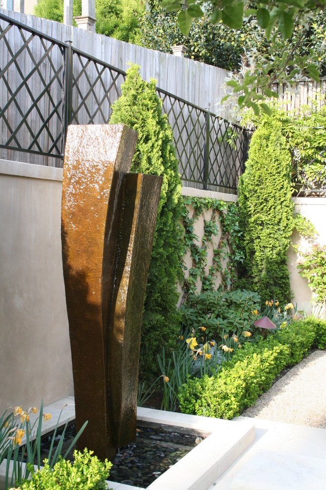 Réalisation d'un petit jardin arrière tradition au printemps avec un point d'eau, une exposition partiellement ombragée et des pavés en pierre naturelle.