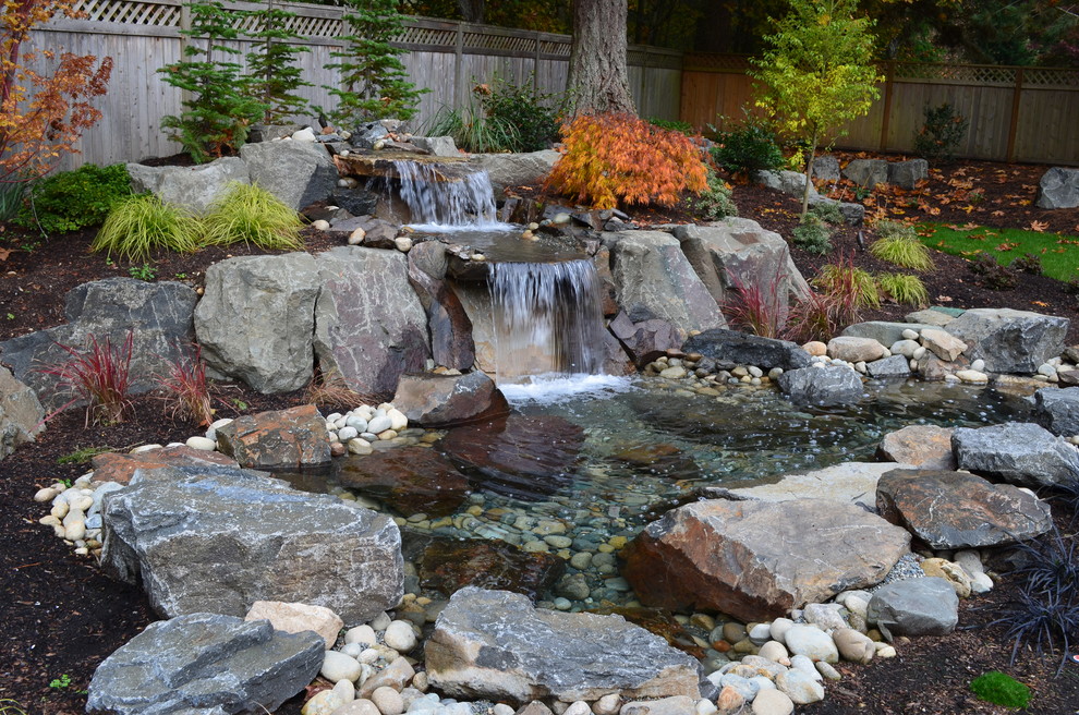 Klassischer Garten hinter dem Haus mit Wasserspiel und Flusssteinen in Seattle