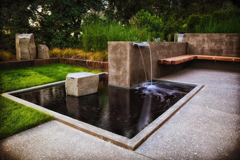 This is an example of a large industrial back formal partial sun garden for spring in Portland with a water feature and concrete paving.