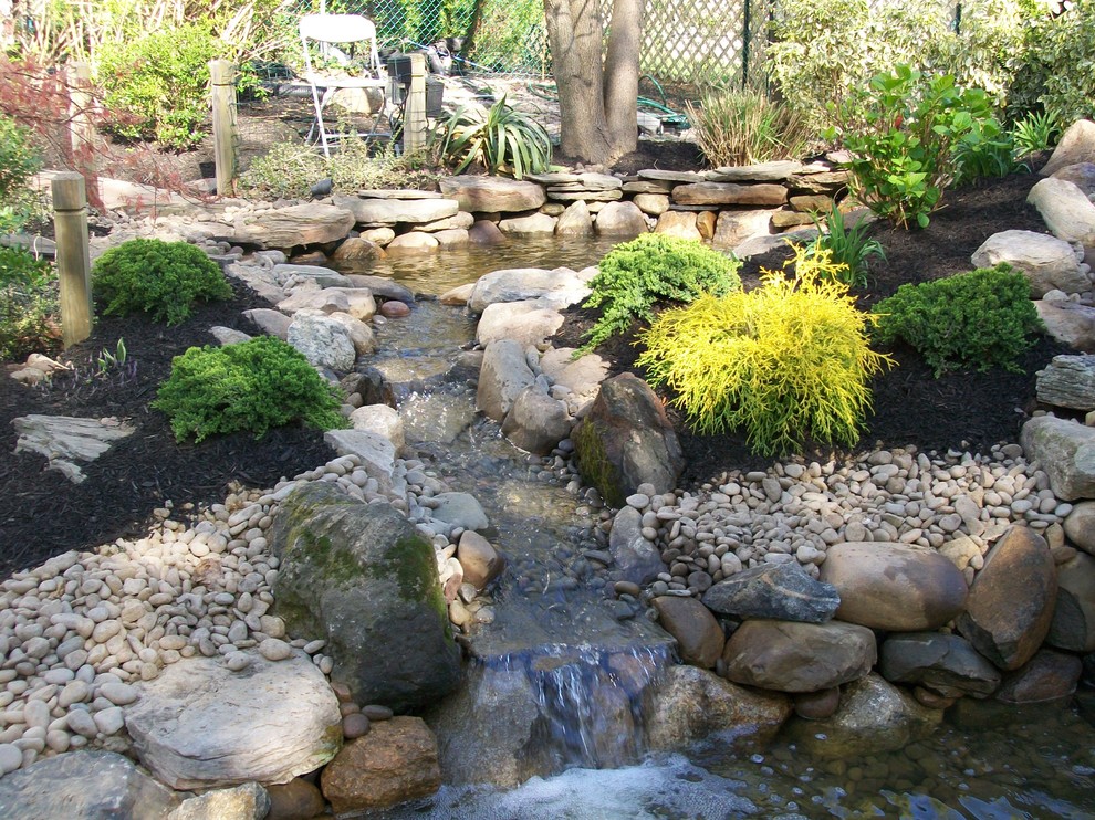 Ejemplo de jardín clásico de tamaño medio en patio trasero con estanque, exposición parcial al sol y gravilla