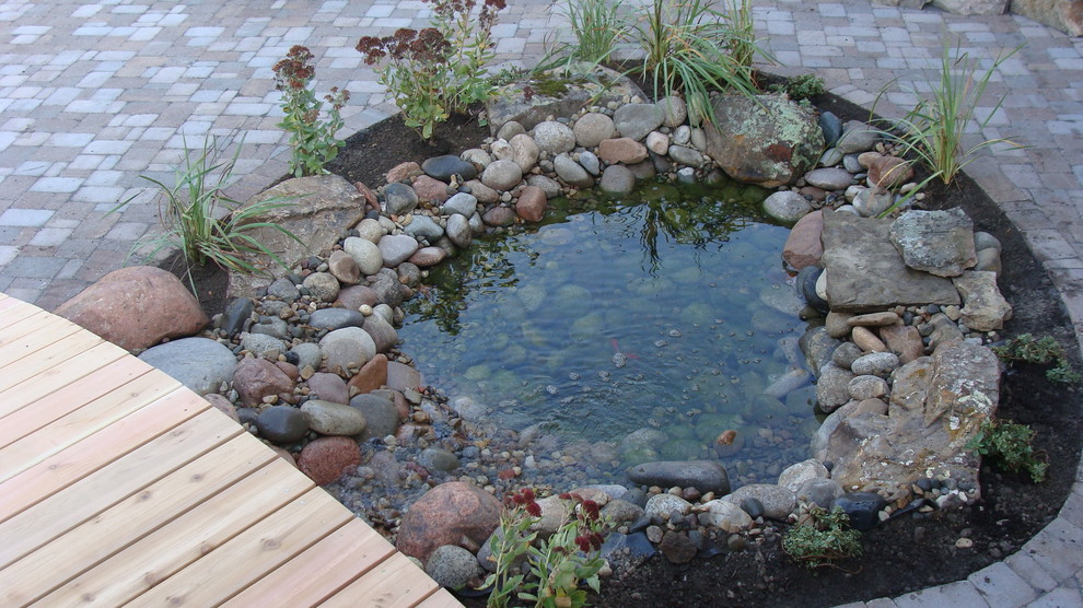 This is an example of a small backyard concrete paver water fountain landscape in Kansas City.