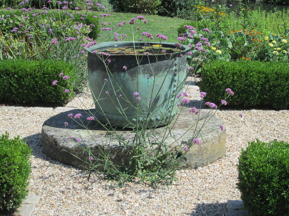 Small classic front xeriscape full sun garden for summer in New York with a water feature and gravel.