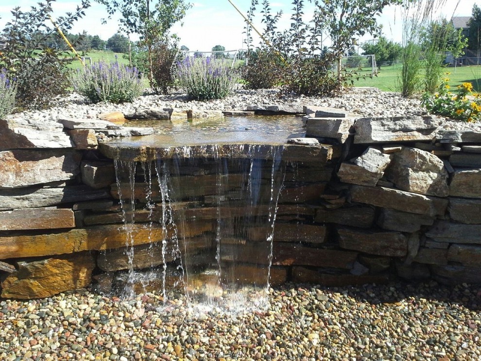 This is an example of a rustic full sun backyard mulch water fountain landscape in Other for summer.