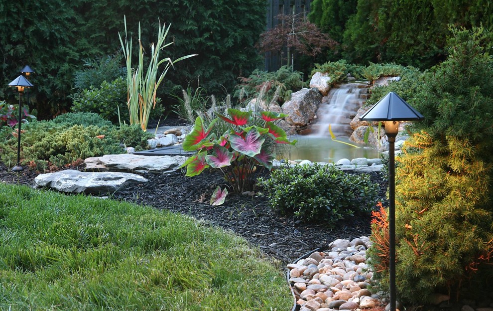 Cette photo montre un jardin arrière chic de taille moyenne avec des pavés en pierre naturelle, un bassin et une exposition partiellement ombragée.