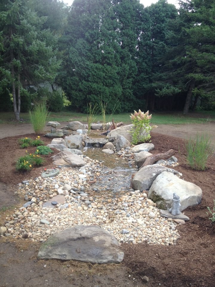 This is an example of a medium sized classic back formal partial sun garden for summer in Providence with a water feature and gravel.