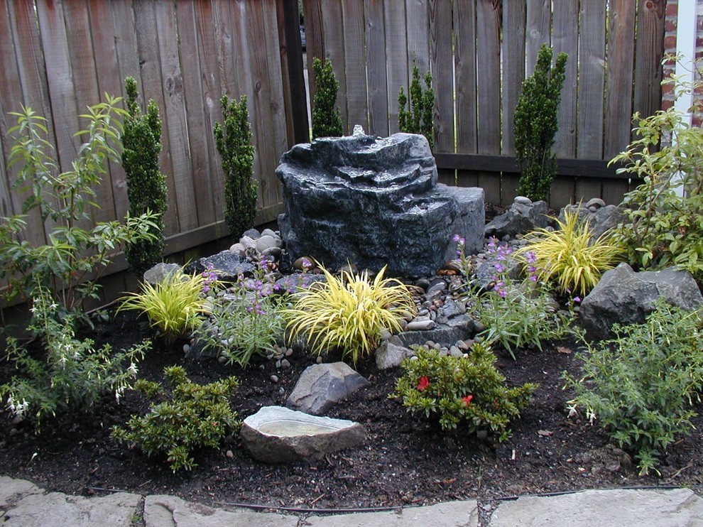 На фото: садовый фонтан среднего размера на заднем дворе в восточном стиле с