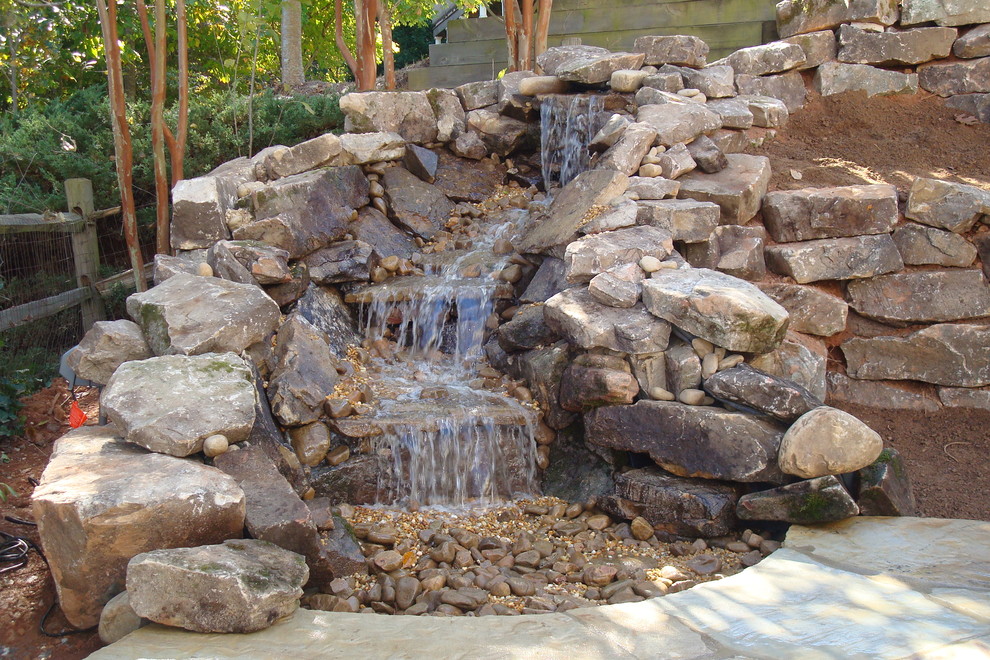 Exempel på en mellanstor modern bakgård, med en fontän och marksten i betong