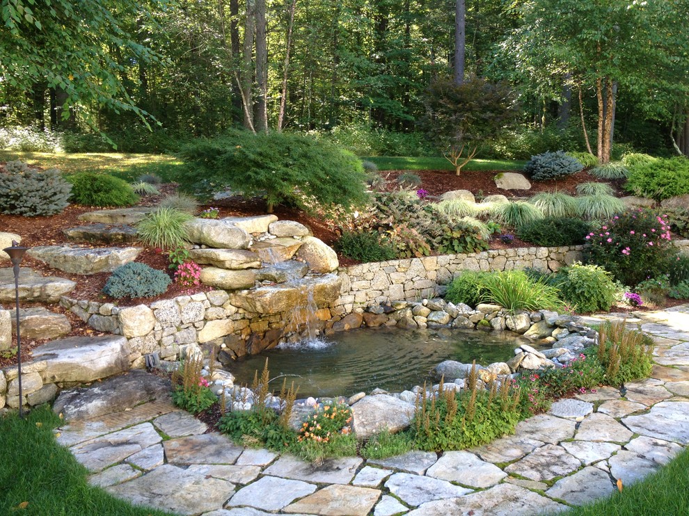 Traditional back garden for summer in Boston with a water feature and natural stone paving.