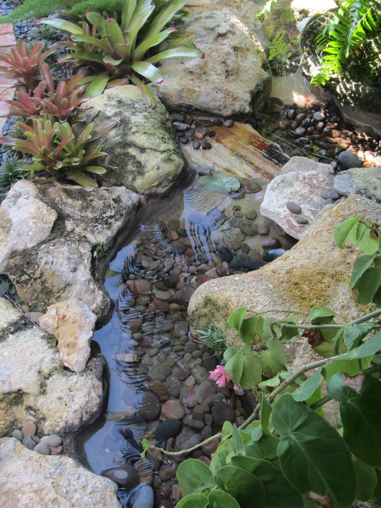 Inredning av en exotisk liten bakgård i skuggan, med en fontän och naturstensplattor