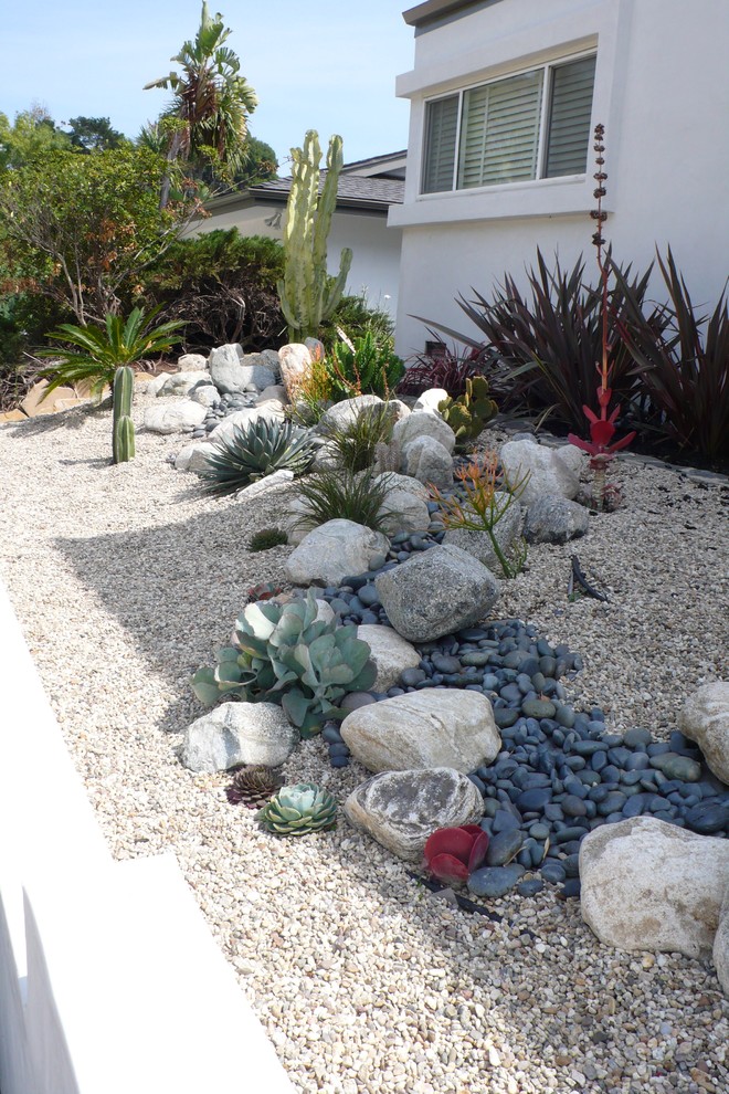 Diseño de jardín de secano minimalista de tamaño medio en patio delantero con exposición parcial al sol, gravilla y muro de contención
