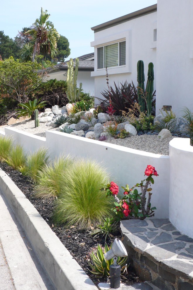 Imagen de jardín de secano minimalista de tamaño medio en patio delantero con muro de contención, exposición parcial al sol y gravilla