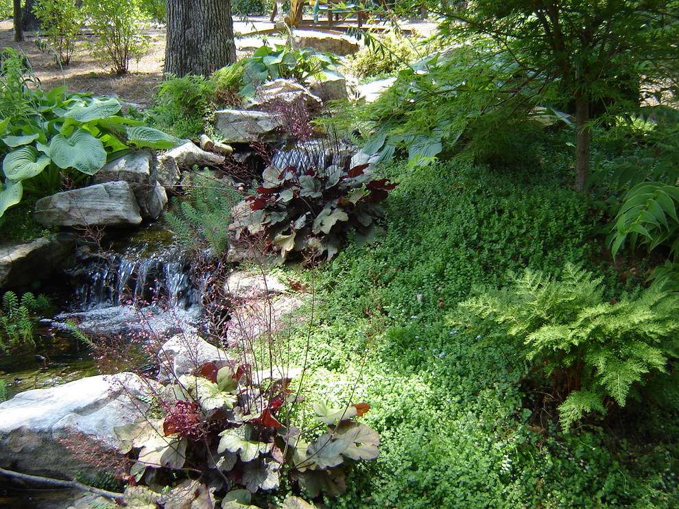 Imagen de jardín clásico en patio trasero con fuente y exposición parcial al sol