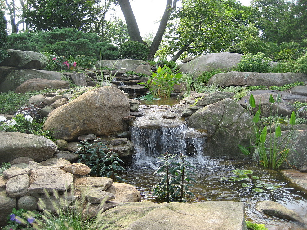 Großer Klassischer Garten hinter dem Haus mit Wasserspiel, direkter Sonneneinstrahlung und Natursteinplatten in Bridgeport