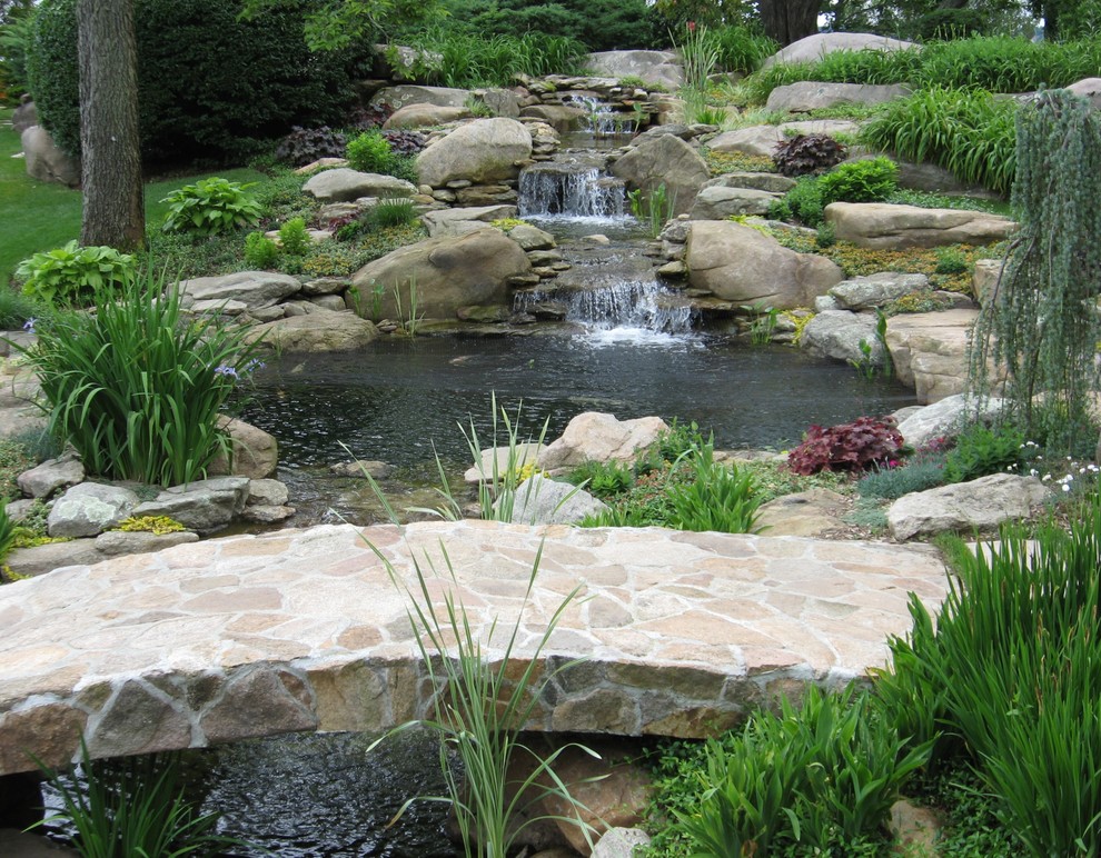 Idée de décoration pour un grand jardin arrière tradition avec une exposition ensoleillée et des pavés en pierre naturelle.
