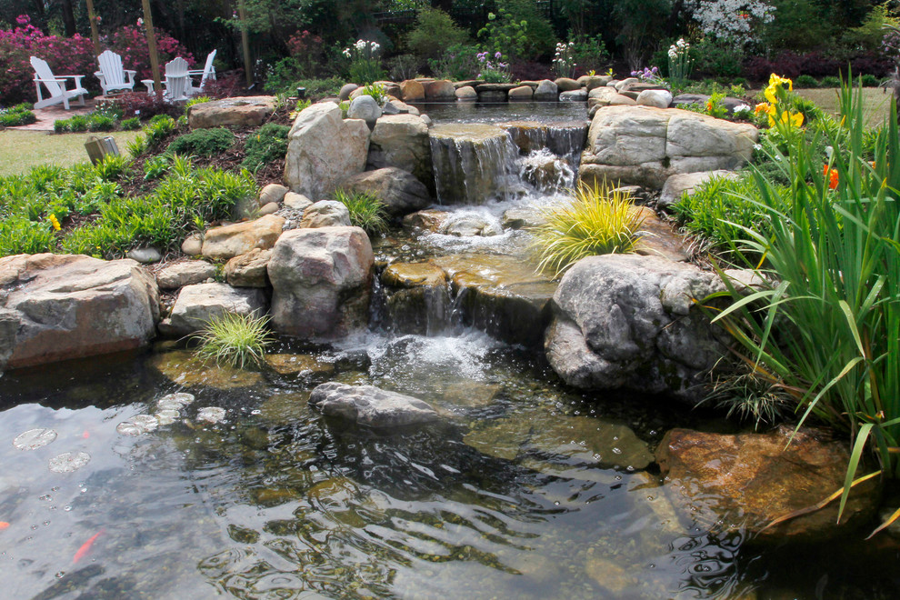 Esempio di un giardino dietro casa con una cascata e sassi di fiume