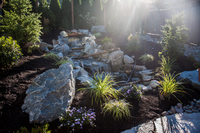 Photo of a mid-sized rustic full sun backyard stone landscaping in Seattle for spring.