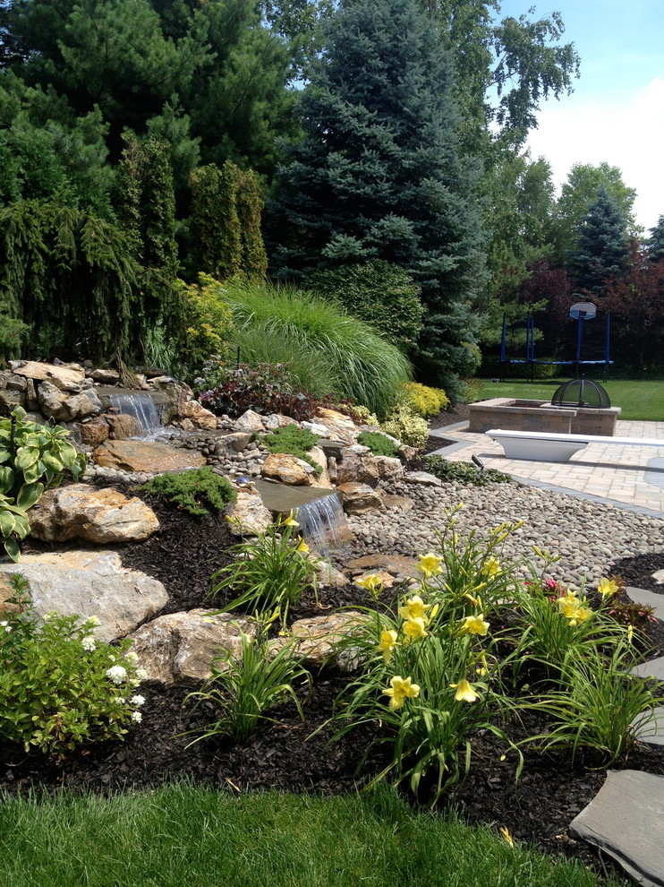 Inspiration for a large modern back full sun garden for summer in New York with a pond and natural stone paving.