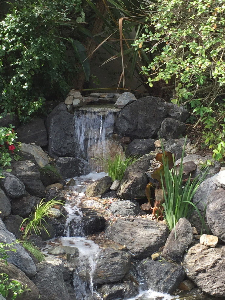 Inspiration pour un jardin arrière chalet avec un bassin, une exposition partiellement ombragée et des pavés en pierre naturelle.