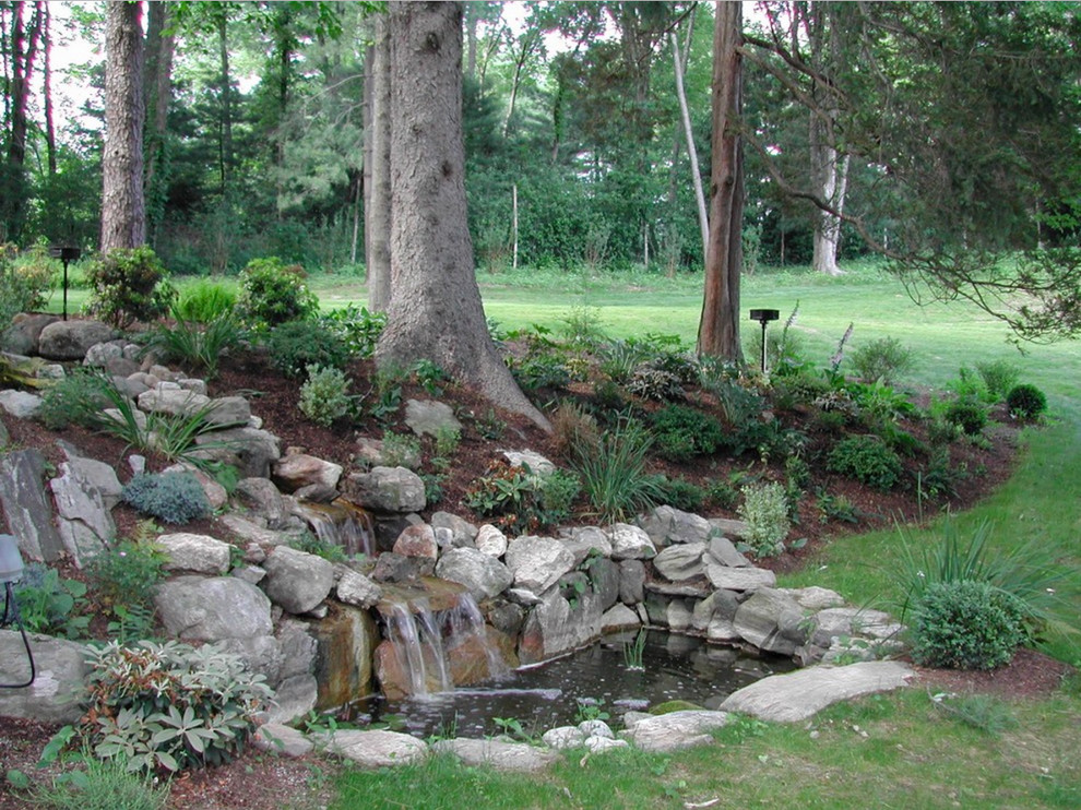 Idées déco pour un grand jardin à la française arrière classique au printemps avec une exposition ensoleillée, des pavés en pierre naturelle et une cascade.