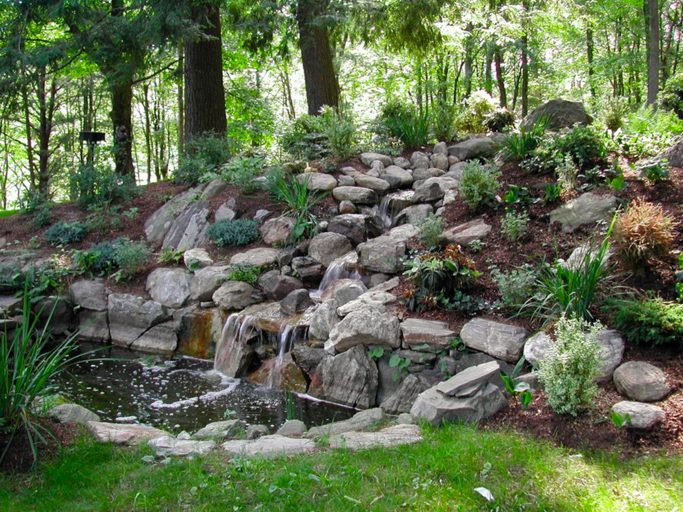 Идея дизайна: большой солнечный, весенний регулярный сад на заднем дворе в классическом стиле с хорошей освещенностью, покрытием из каменной брусчатки и водопадом