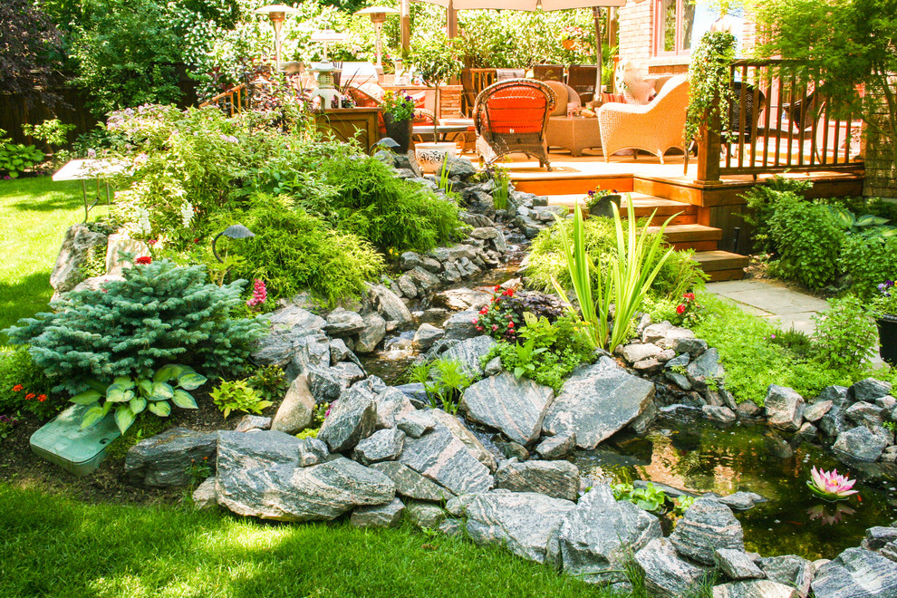 Ejemplo de jardín clásico de tamaño medio en verano en patio trasero con estanque, exposición parcial al sol y adoquines de piedra natural