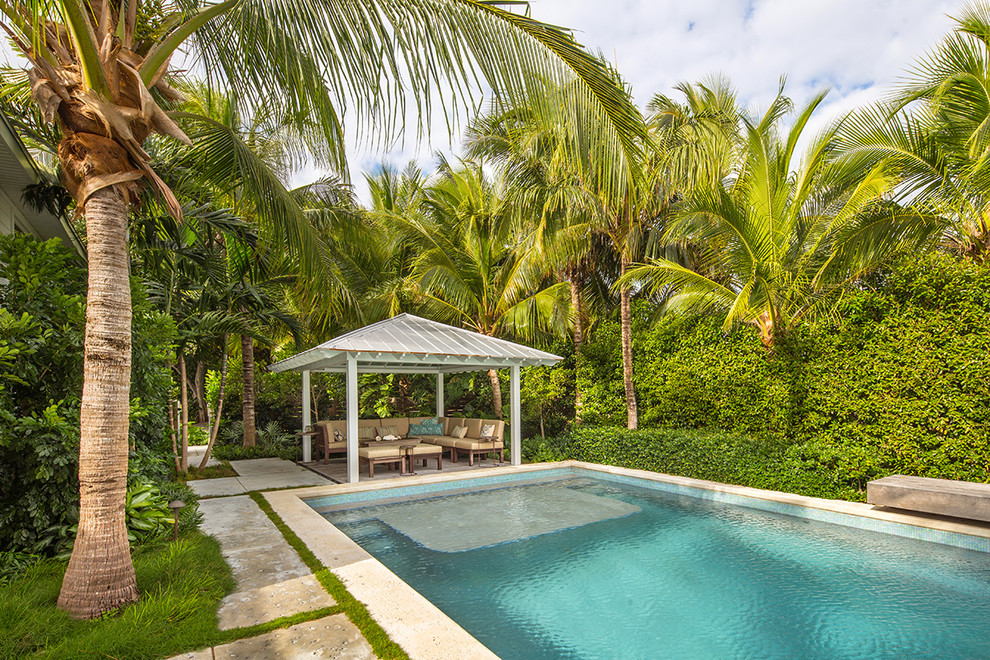 Foto di un grande giardino tropicale esposto in pieno sole dietro casa con pavimentazioni in cemento