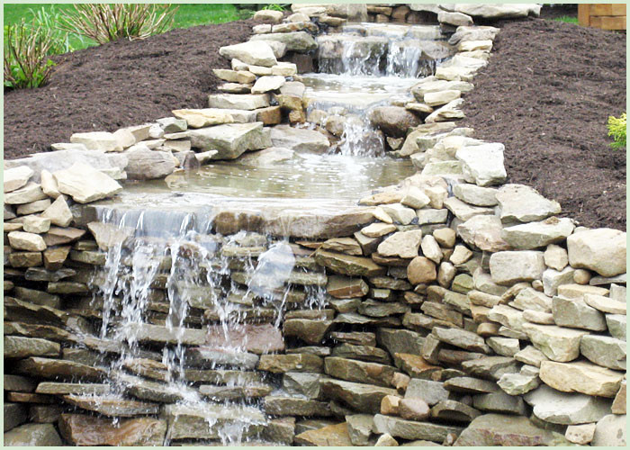Inspiration for a large traditional partial sun backyard stone water fountain landscape in Cleveland for summer.