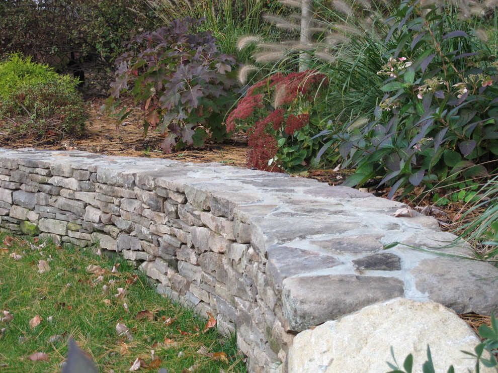 Imagen de jardín clásico en patio trasero con exposición reducida al sol y adoquines de piedra natural