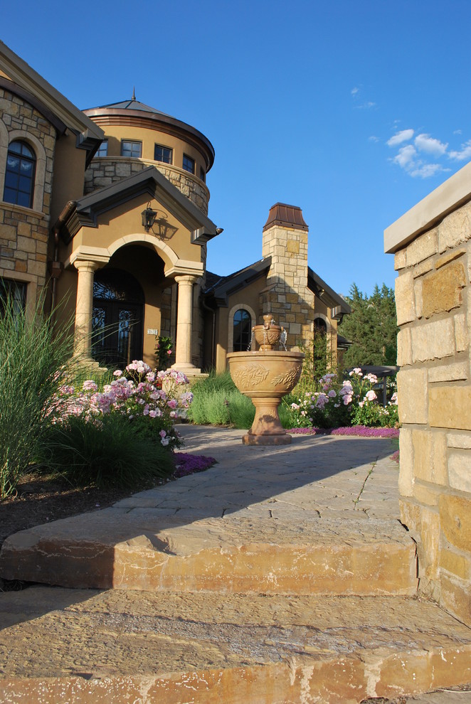 This is an example of a large rustic front formal partial sun garden in Salt Lake City with a garden path and natural stone paving.